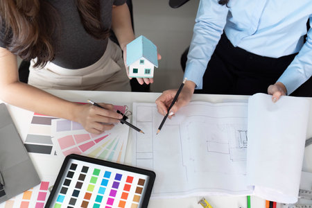 Collaborative Design. Architects discussing sustainable home project with model and blueprints.の写真素材