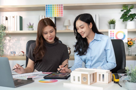 Architectural Design. Women collaborating on a project with color palettes and a model.
