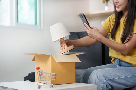 Online shopping. Woman taking a photo of a lamp after unboxing.の写真素材