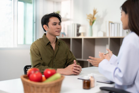 Nutrition Consultation. Male patient discussing health with a dietitian in a modern clinic.の写真素材