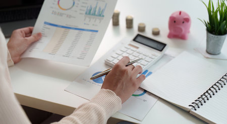 Financial Analysis. Woman reviewing financial reports with calculator and pen.の写真素材