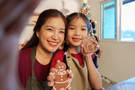 Holiday Treats. Mother and daughter proudly displaying their decorated gingerbread cookies.