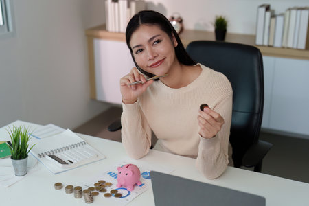 Financial Reflection. Woman contemplating savings while holding a coin and pen.の写真素材