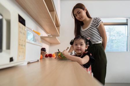 A woman is feeding a young girl a saladの写真素材