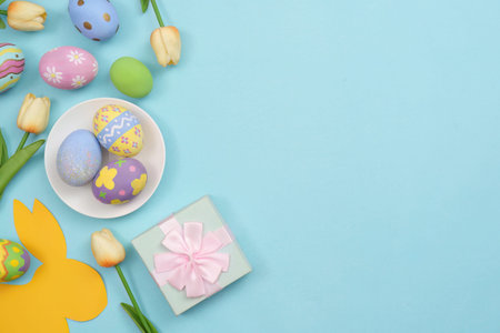Easter Joy. Colorful eggs and gift box with tulips on soft blue background.