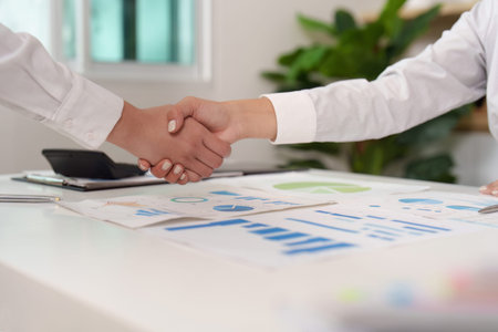 Business Agreement. Two professionals shaking hands over financial documents.