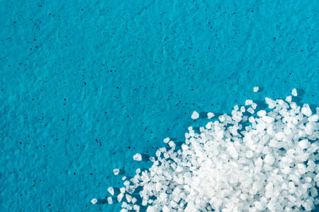 white crystals of coarse salt on blue background.