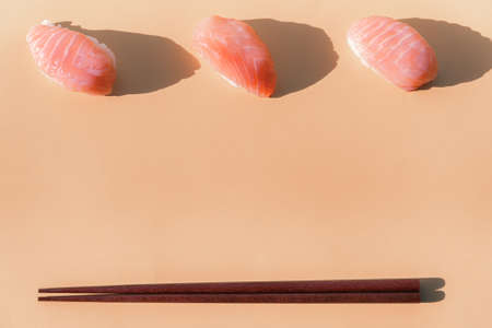 salmon sushi closeup with chopsticks on beige backgroundの写真素材