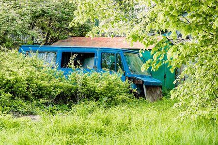 an old blue car is standing in the grassの写真素材