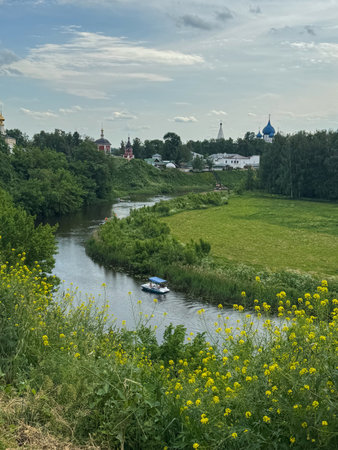 A small boat glides along a curved river surrounded by vibrant green fields.