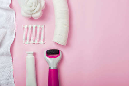 Flat lay of female hygiene accessories on pastel pink background. The set includes cotton swabs and sponges; towel; hand cream; bath sponge; massager and electric roller nail file for rough skinの写真素材