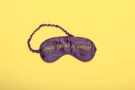 Purple satin  sleeping mask on yellow background. Mininal flat lay concept.の写真素材