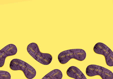 Purple satin  sleeping mask pattern on yellow background. Mininal flat lay concept.