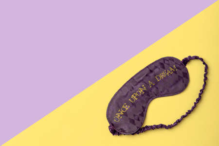 Purple satin  sleeping mask on yellow and purple background with space for text. Minimal flat lay concept.の写真素材
