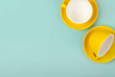 Top view on yellow cups and saucers on blue background