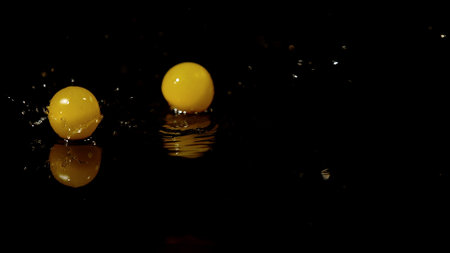 two yellow cherry tomatoes on a dark background
