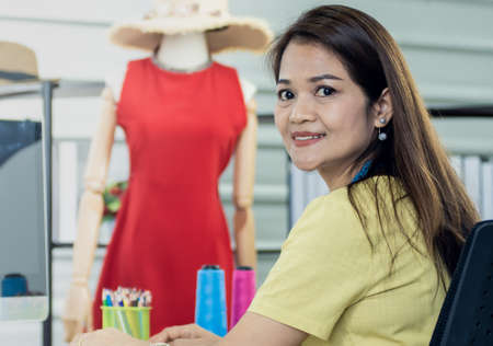 Portrait of Asian female fashion designer working in cloth shop and smilingの写真素材