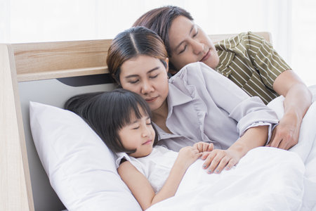 An asian family is sleeping well on the bed in their houseの写真素材
