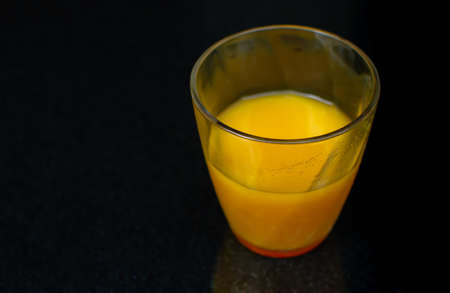 Portrait of a glass of orange juice on black tableの写真素材