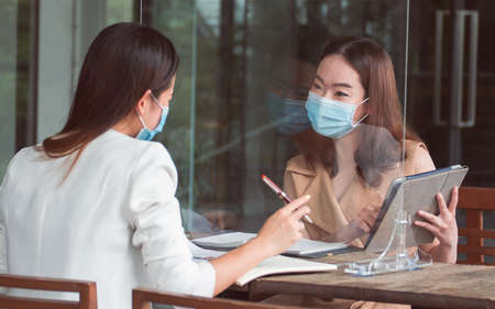 Asian business woman wearing mask and keeping social distancing while working. New Normal and Business Concept.の写真素材