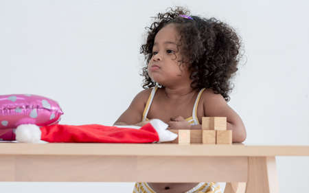 Little african black girl with afro hair playing toys in living room at homeの写真素材