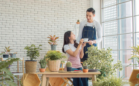Asian young couple spending time together in holiday and gardening plants at home. Nature, Hobby, Interior and Lover Concept.の写真素材