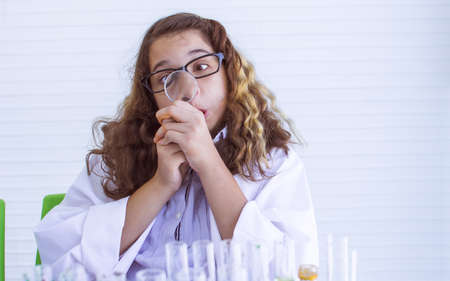 Caucasian female teenage student making funny face and using magnifying glass while staying in laboratory at school. Education Concept.の写真素材