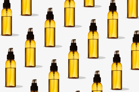 Pattern of yellow transparent oil bottle on white background. Mockup of skincare products. Creative...