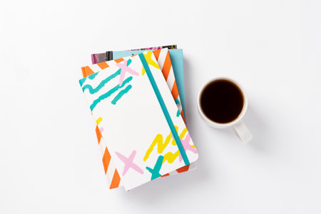 A stack of color notepads with cup of coffee on a white minimal background. Study, office, business...