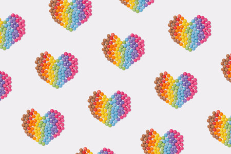 Brightly coloured sweets form a heart shape on white background. Rainbow colored candy. Happiness...