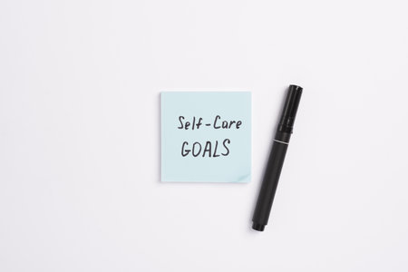 Paper note with words 2025 Self Care Goals and black marker on a white minimal background. Concept...