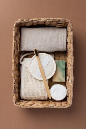 Top view of bathroom tools and organic cosmetic products in woven basket on brown background...