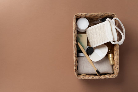 Top view of bathroom tools and organic cosmetic products in woven basket on brown background...