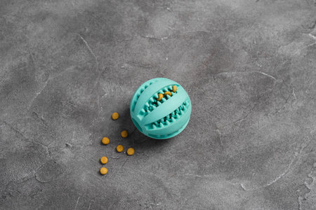 Ball for dog treats on gray concrete background. Toy for preventing development of caries of dogs,...