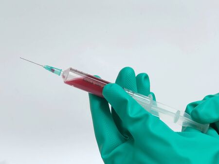Doctor's hand in glove holding medical injection syringe, isolated on white background