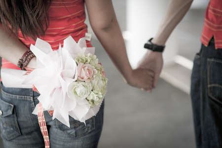 Loving couple is walking together and holding hands with bouquetの写真素材