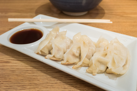 Gyoza (Jiaozi) on white dish with soy sauceの写真素材