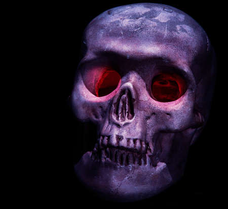 A creepy skull head with red eyes on black backgroundの写真素材