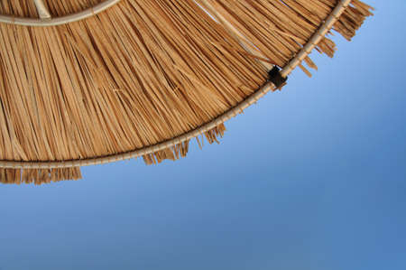 A bright blue sky with palm parasolの写真素材