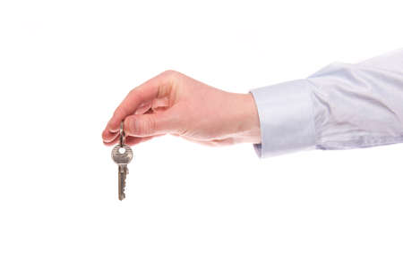 A hand of a businessman keep up a house key isolated on a white backgroundの写真素材