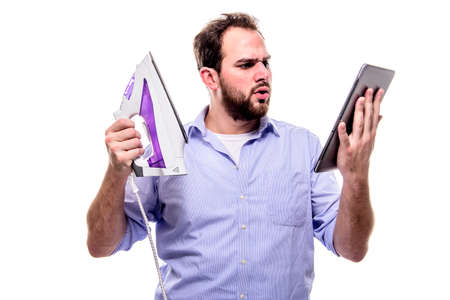 Man with iron and tablet searches for the manual, concept of women empowerment, clumsiness, household and online manualsの写真素材
