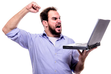 Bearded man shouting angrily at his laptop and waving his fist