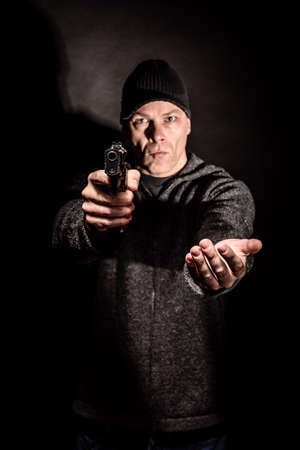 Robber with a gun holds his hand out for the money, concept of danger, threat and extortionの写真素材