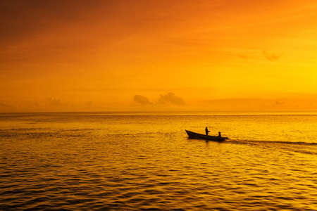People in a boat on a sea at sunriseの写真素材