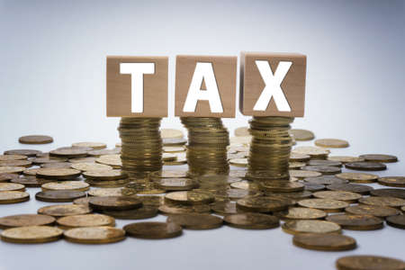 Word tax on wooden block with stacked gold coins. Tax concept.の写真素材