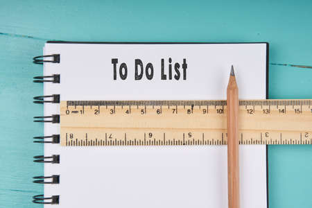 To Do List word on notebook, wooden ruler and pencil on blue wooden background. Top view.の写真素材