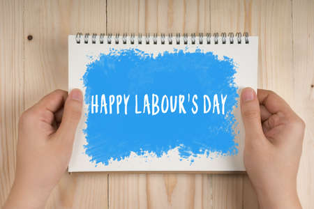 Woman holding notebook in hands with Happy Labours Day words. Business Concept.の写真素材