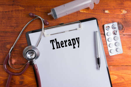 Stethoscope, syringe, pills with Therapy words on wooden background. Medical Concept.の写真素材