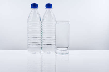 Plastic bottle and glass of mineral water on white background.の写真素材