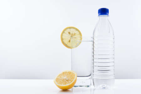 Mineral water glass with lemon and a plastic water bottles on a white background.の写真素材